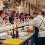 Guests seated along the counter watching a chef prepare food at El Camino Restaurant