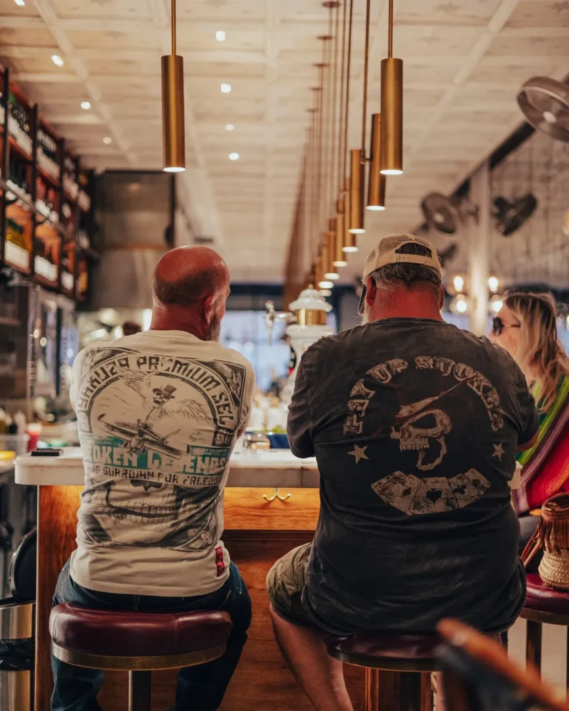 Two guests on burgundy stools at the counter seen from behind at El Camino Restaurant