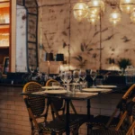Rattan-chaired table set against an antiqued mirror wall under glass globe lights at El Camino Restaurant