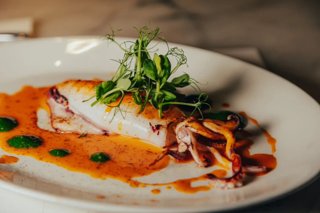 Grilled squid in a paprika sauce with herb oil and pea shoots at El Camino Restaurant