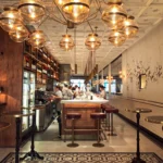 Interior with a brass globe chandelier over the open kitchen counter and mosaic floor at El Camino Restaurant