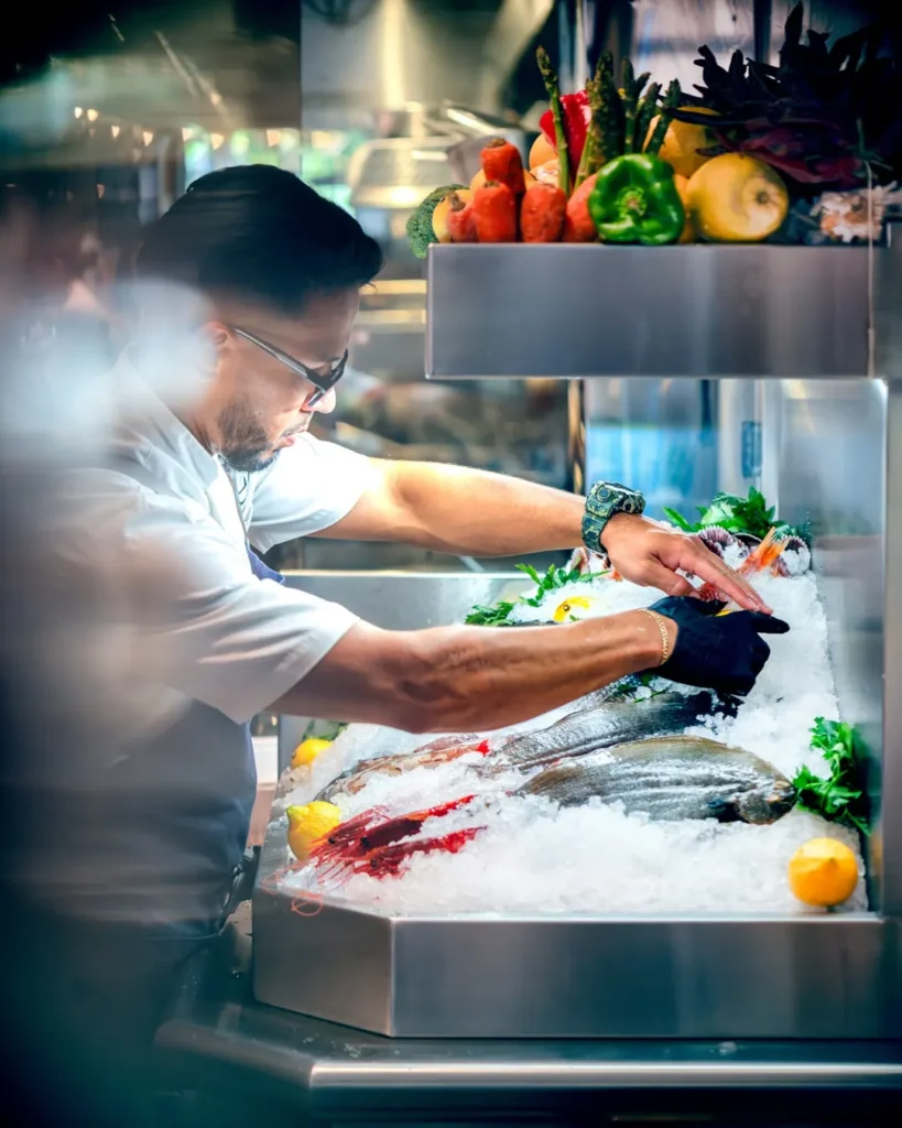 Chef arranging fresh fish and prawns on the iced seafood display at El Camino Restaurant