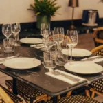 Black marble table set with monogrammed glassware and bistro chairs at El Camino Restaurant
