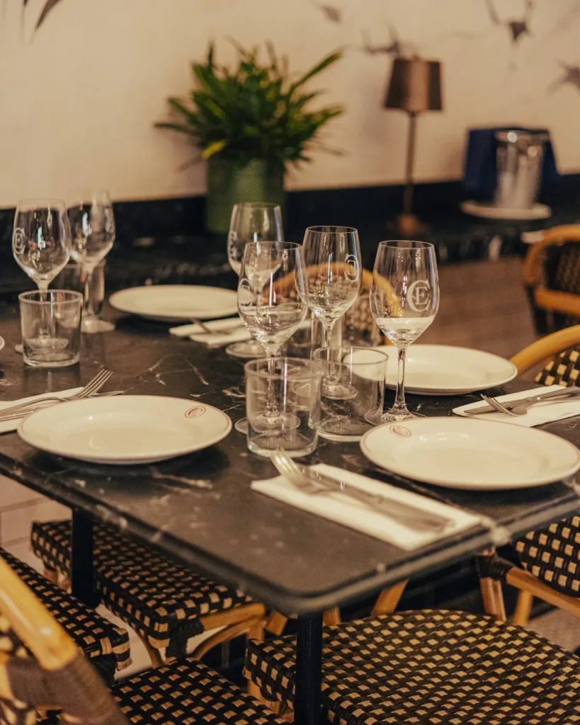 Black marble table set with monogrammed glassware and bistro chairs at El Camino Restaurant