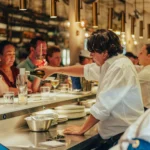 Server pouring white wine for guests along the counter at El Camino Restaurant