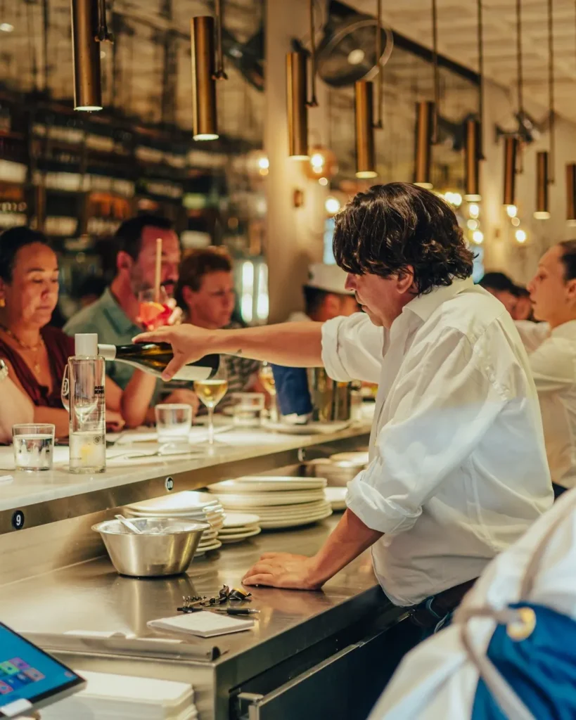 Server pouring white wine for guests along the counter at El Camino Restaurant