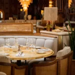 Curved banquette and cane chairs around a marble table beneath a rattan lamp at Gigi Rigolatto Paris
