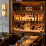 Onyx bar counter with cane stools and a backlit wall of spirits at Gigi Rigolatto Paris