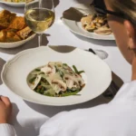 Green bean salad with mushrooms and shaved cheese served with white wine at Gigi Rigolatto Paris