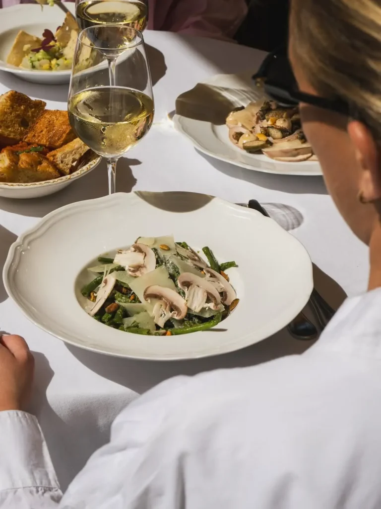 Green bean salad with mushrooms and shaved cheese served with white wine at Gigi Rigolatto Paris