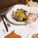 Linguine with clams and herbs beside a glass of rosé at Gigi Rigolatto Paris