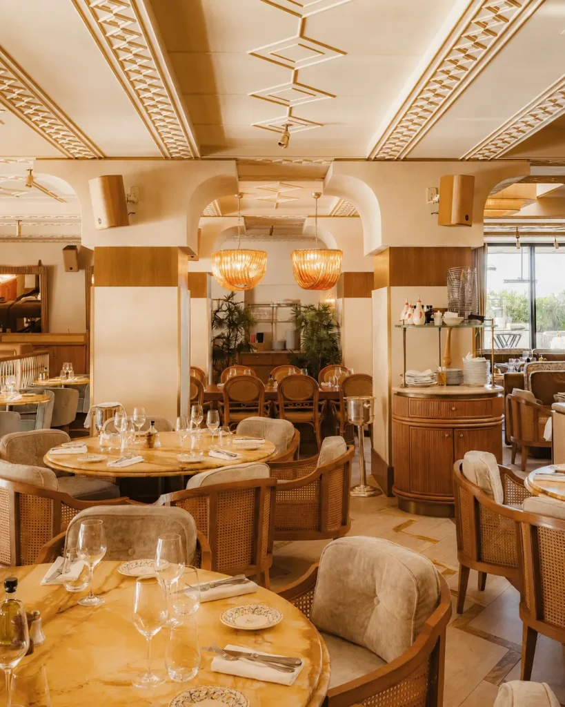Art Deco dining room with onyx tables, cane armchairs and rattan pendants at Gigi Rigolatto Paris
