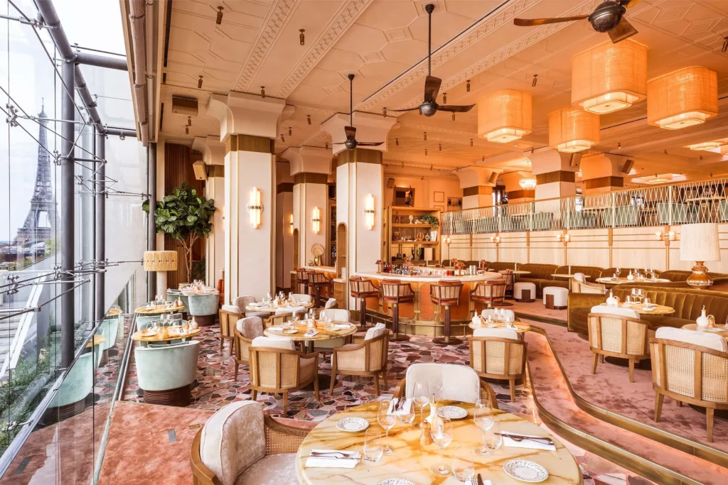Art Deco dining room with terrazzo floor, cane chairs and an Eiffel Tower view through the windows at Gigi Rigolatto Paris