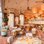 Art Deco dining room with terrazzo floor, cane chairs and an Eiffel Tower view through the windows at Gigi Rigolatto Paris
