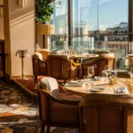 Cane armchairs and marble tables by the windows over a terrazzo floor at Gigi Rigolatto Paris
