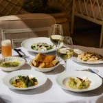 Spread of salad, risotto, bread and white wine on a white-clothed table at Gigi Rigolatto Paris