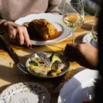 Gnocchi with sage in a pan beside a roast dish and monogrammed Gigi plate at Gigi Rigolatto Paris