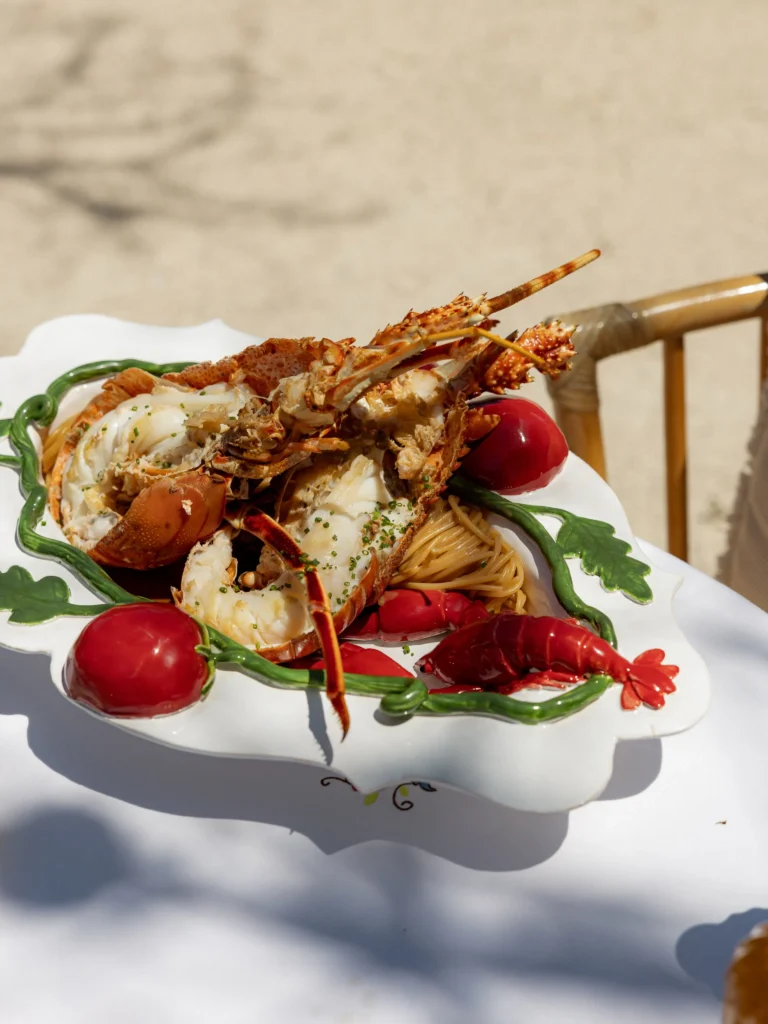 Lobster over pasta on a vegetable-motif platter in bright sunlight at Gigi Rigolatto Paris