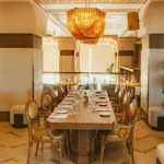 Long private dining table under an amber glass chandelier at Gigi Rigolatto Paris