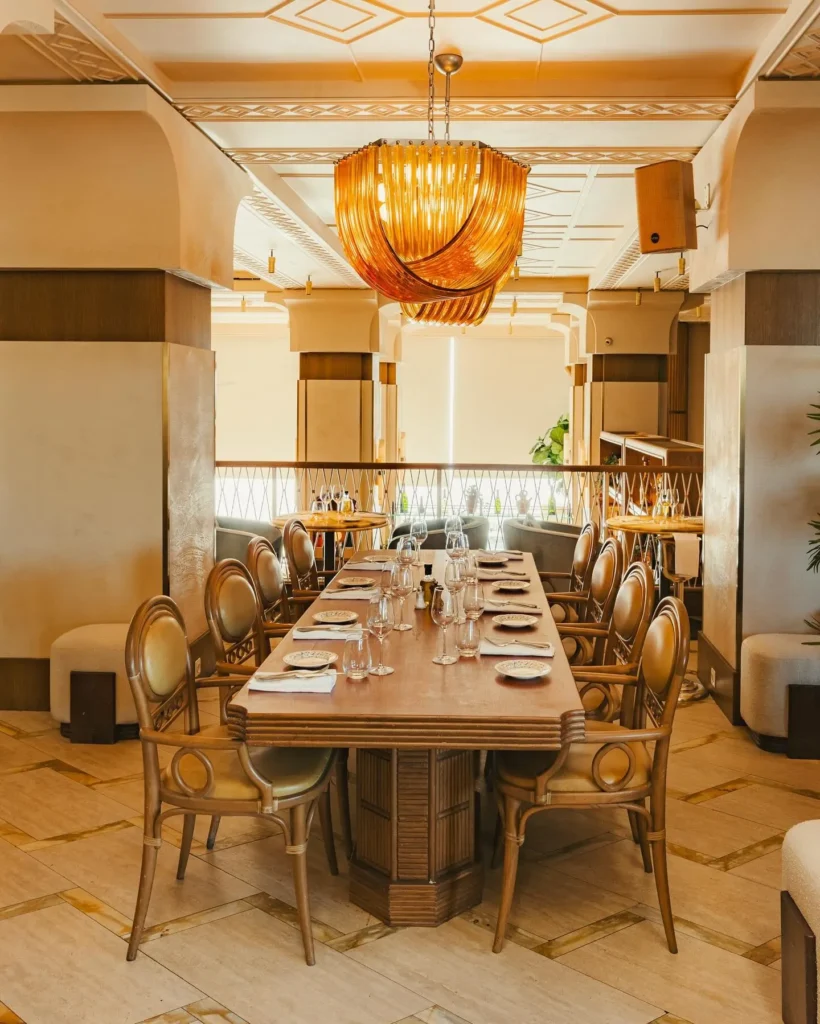 Long private dining table under an amber glass chandelier at Gigi Rigolatto Paris