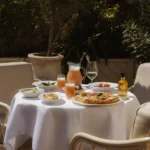 Pizza, sides and pink drinks on a terrace table in the sun at Gigi Rigolatto Paris