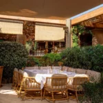 Cushioned banquette table under sail shades and bamboo blinds at Gigi Rigolatto Saint-Tropez