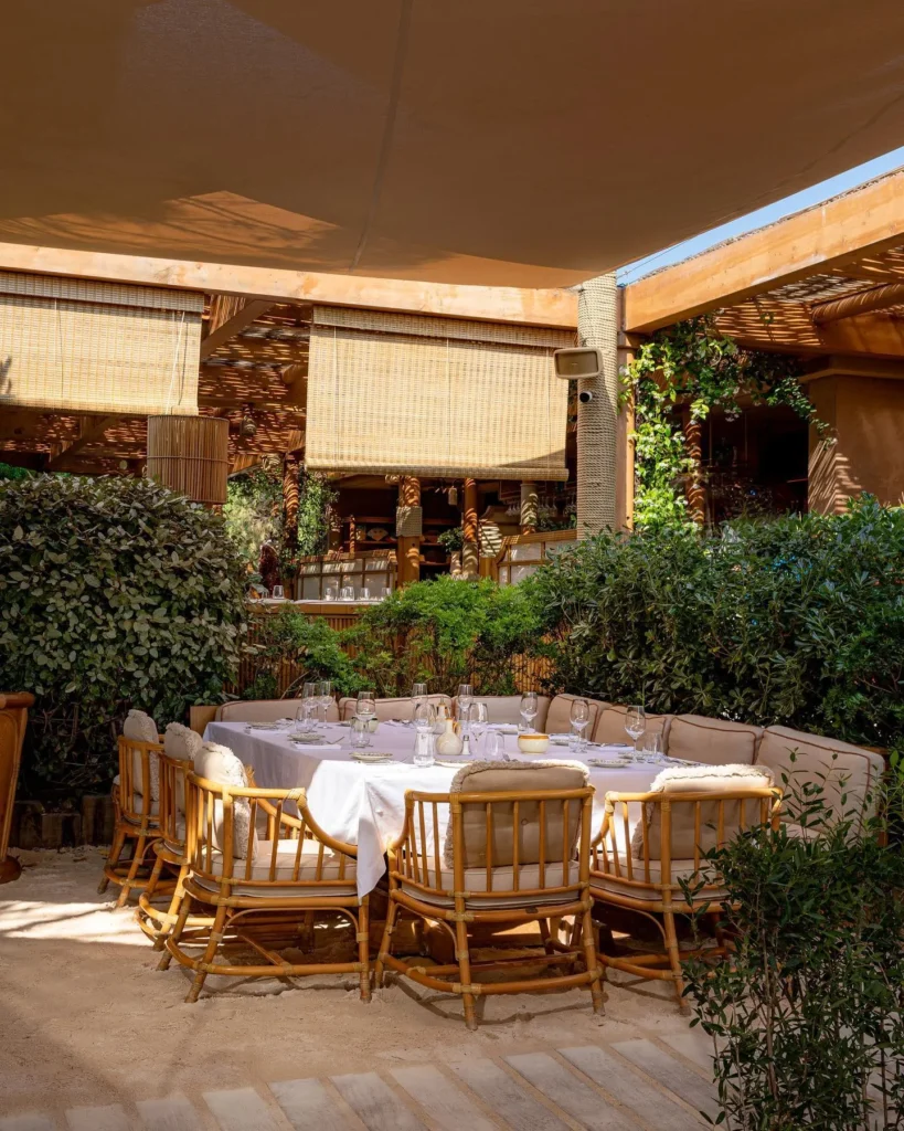 Cushioned banquette table under sail shades and bamboo blinds at Gigi Rigolatto Saint-Tropez