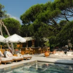 Poolside bar with rattan stools, sunbeds and a fringed umbrella at Gigi Rigolatto Saint-Tropez