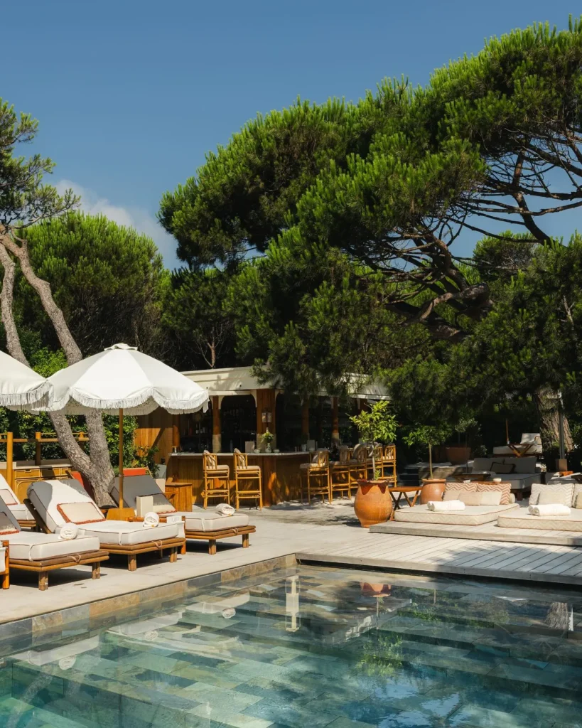 Poolside bar with rattan stools, sunbeds and a fringed umbrella at Gigi Rigolatto Saint-Tropez