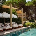 Cushioned loungers under sail shades and parasols beside the pool at Gigi Rigolatto Saint-Tropez