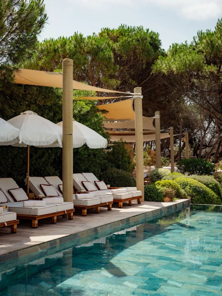 Cushioned loungers under sail shades and parasols beside the pool at Gigi Rigolatto Saint-Tropez