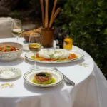 Tuna tartare topped with caviar beside burrata and grissini on a garden table at Gigi Rigolatto Saint-Tropez