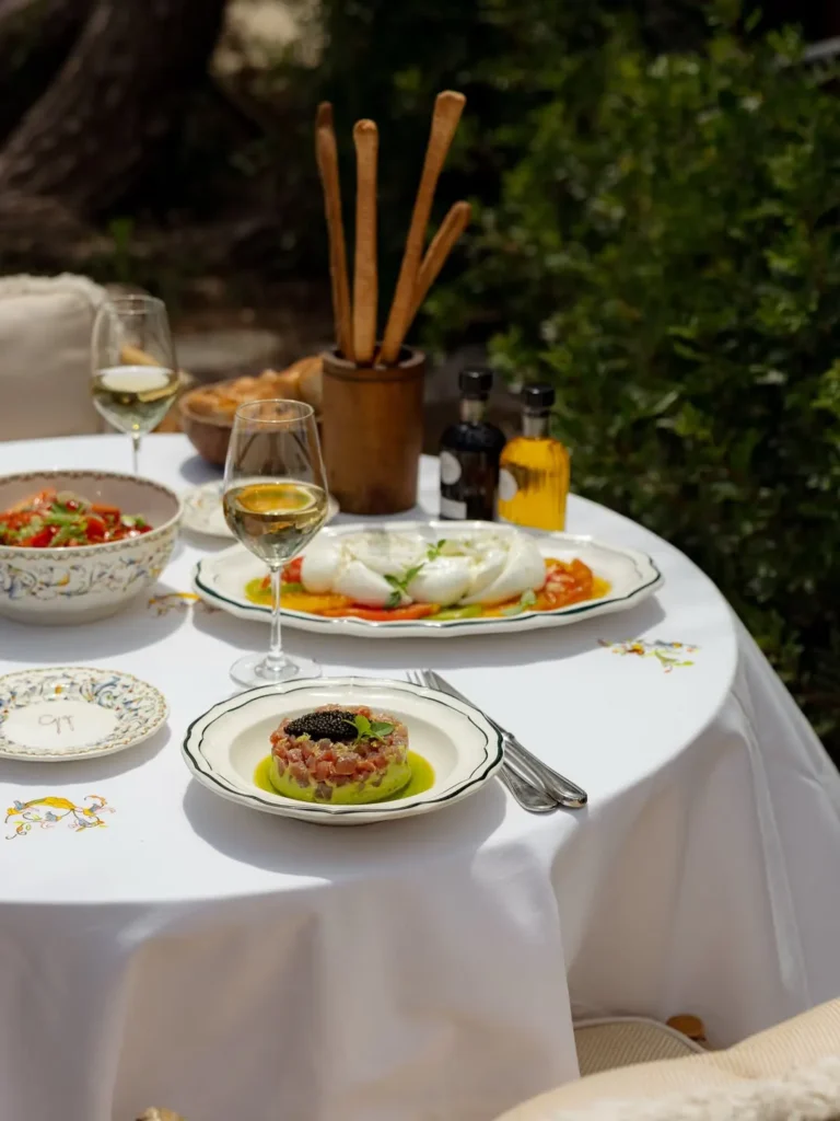 Tuna tartare topped with caviar beside burrata and grissini on a garden table at Gigi Rigolatto Saint-Tropez