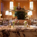 Veined marble console with a crystal decanter and brass gallery lamps at Girafe Paris