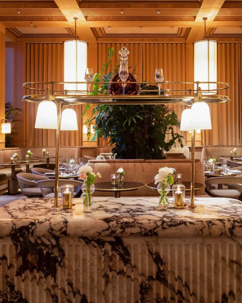 Veined marble console with a crystal decanter and brass gallery lamps at Girafe Paris