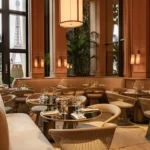 Wire chairs and marble tables by tall windows framing the Eiffel Tower at Girafe Paris