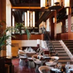 Art Deco dining room with red marble floor, wire chairs and a carpeted staircase at Girafe Paris