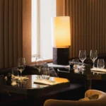 Intimate set tables lit by a marble table lamp with velvet armchairs at Girafe Paris