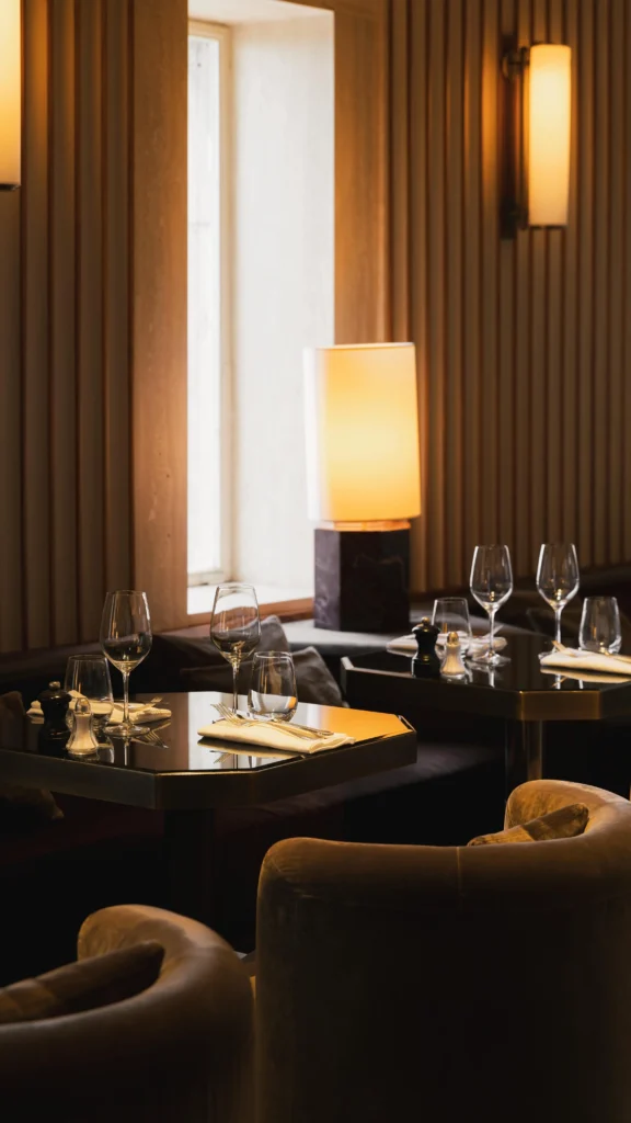 Intimate set tables lit by a marble table lamp with velvet armchairs at Girafe Paris