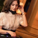 DJ in a lace blouse mixing at the decks in warm light at Girafe Paris