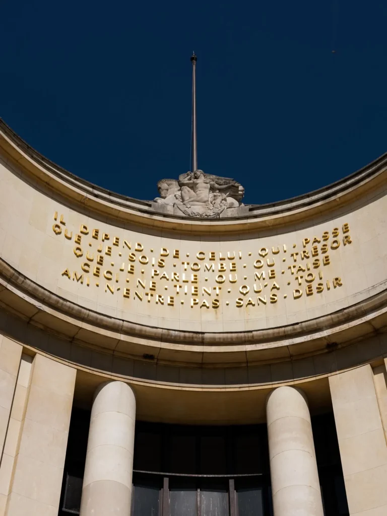 Curved Palais de Tokyo facade with the gold Paul Valéry inscription and a stone sculpture at Girafe Paris