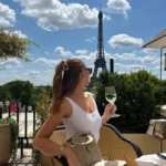 Guest with a glass of white wine gazing toward the Eiffel Tower on the terrace at Girafe Paris