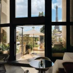 View from the lounge through open doors to the terrace and Eiffel Tower at Girafe Paris