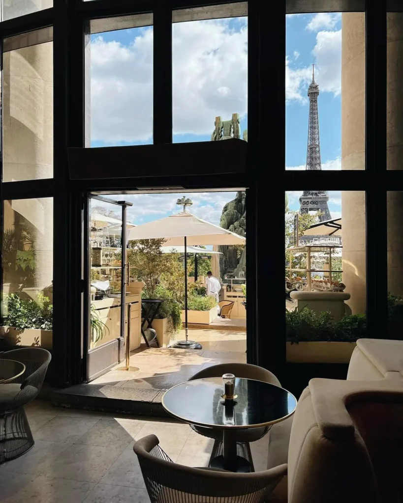 View from the lounge through open doors to the terrace and Eiffel Tower at Girafe Paris