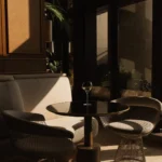 Wire lounge chairs and a small table in golden-hour light by the windows at Girafe Paris