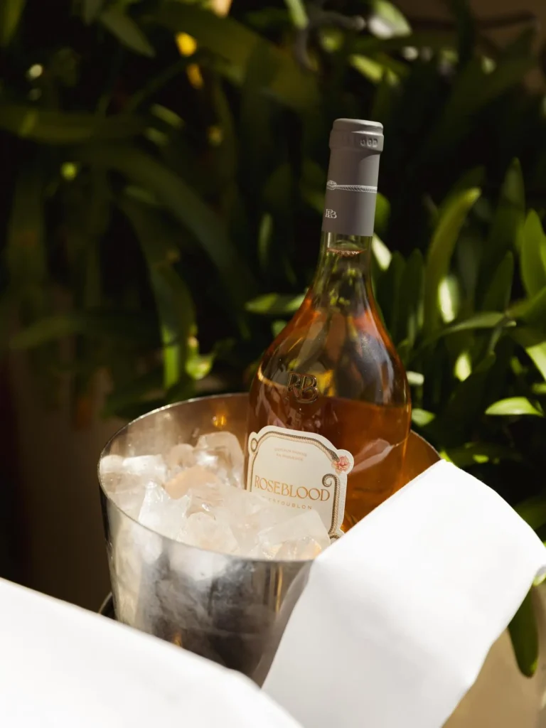 Bottle of Roseblood rosé chilling in an ice bucket among greenery at Girafe Paris