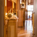 Gold GIRAFE lettering etched on a glass door looking into the wood-panelled interior at Girafe Paris