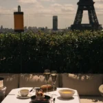 Dessert and champagne on a terrace table with the Eiffel Tower behind at Girafe Paris