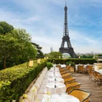 Long white-clothed terrace tables and rattan chairs facing the Eiffel Tower at Girafe Paris