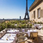 Terrace banquette and tables with the Eiffel Tower and Paris skyline beyond at Girafe Paris
